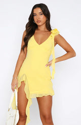dresses : Scarlett – Élégante robe courte asymétrique à volants avec détail floral sur l’épaule in Jaune van Seroa